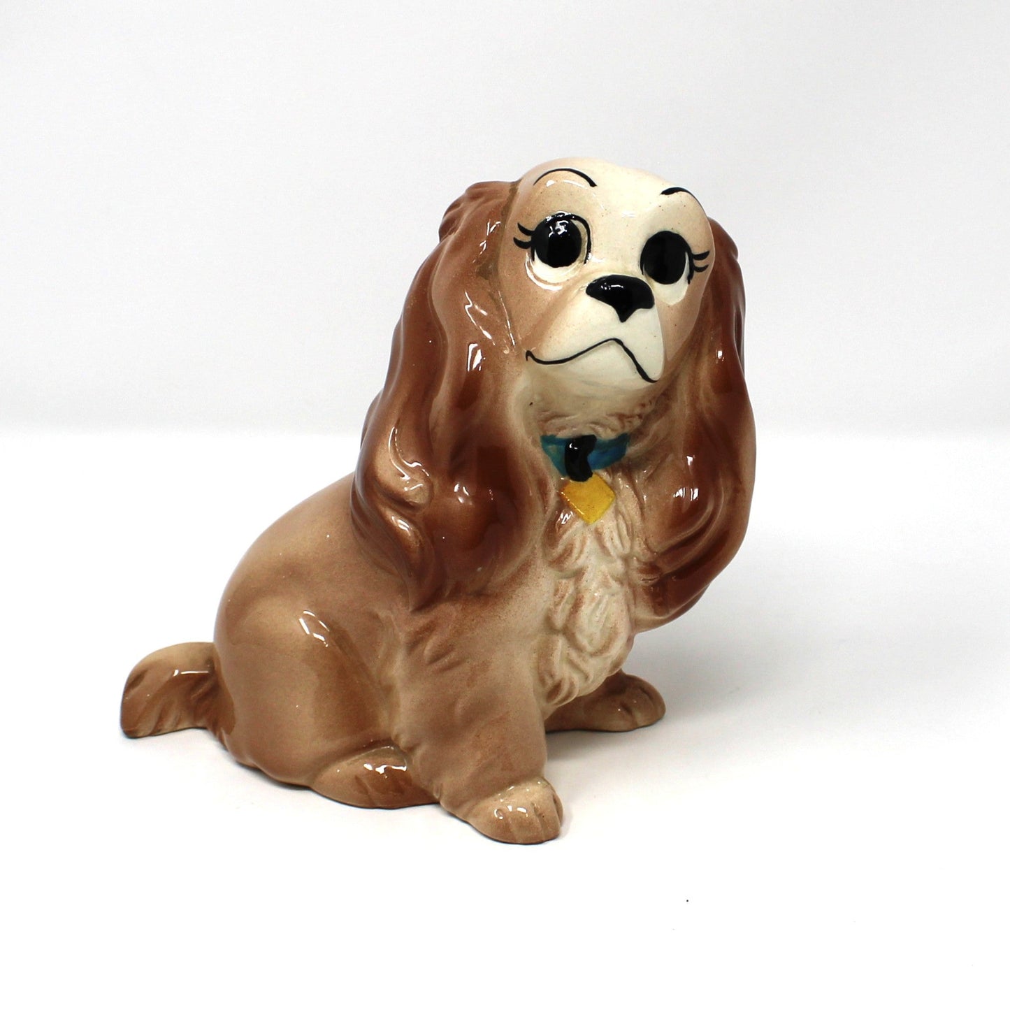 A vintage Hagen-Renaker ceramic coin bank.  Disney's "Lady" from the Movie, Lady and the Tramp. Cocker Spaniel dog wearing a small blue and yellow collar.