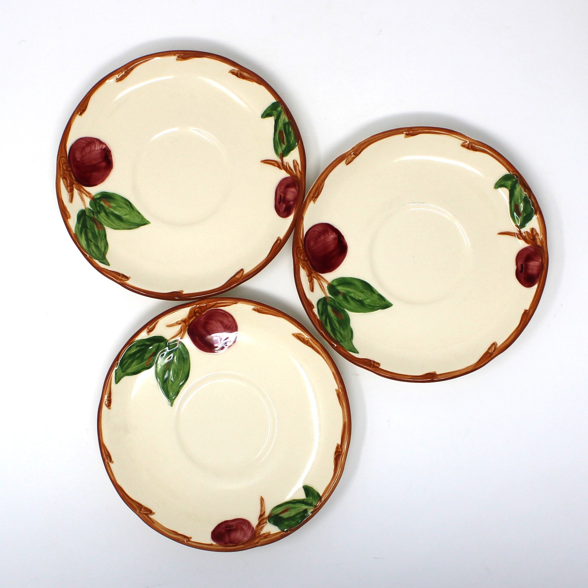 View from above, Set of 3 vintage Franciscan Apple saucers.  Hand painted apples and green leaves on a cream-colored background.