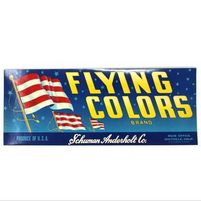A vintage paperboard sign for the Flying Colors brand, featuring a blue starry background, yellow lettering, and American flag graphics, with 'Schuman Anderholt Co.' printed at the bottom.