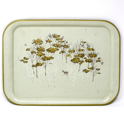 A vintage rectangular metal tray with rounded corners, featuring a light beige  background, a gold-toned rim, and an  illustration of birch trees with gold foliage and a small deer.