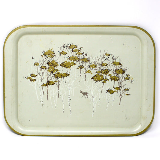 A vintage rectangular metal tray with rounded corners, featuring a light beige  background, a gold-toned rim, and an  illustration of birch trees with gold foliage and a small deer.
