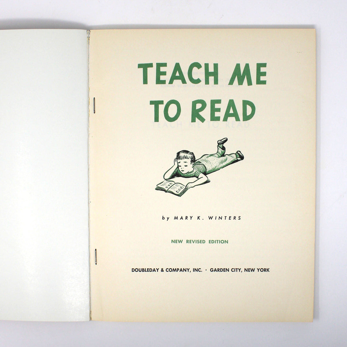 An open vintage book or binder showing the title page 'TEACH ME TO READ' in green text on an off-white page, photographed against a plain white background.