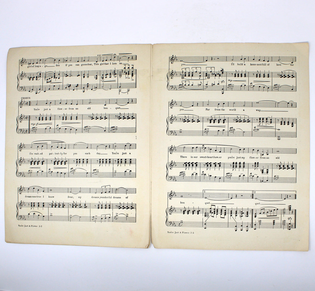 An open vintage sheet music with aged, yellowed pages displaying printed musical notation