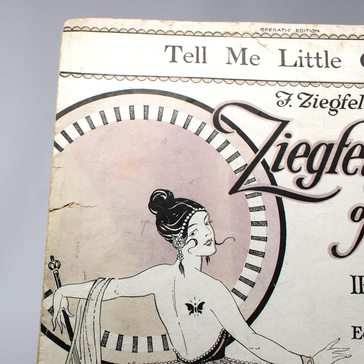 Vintage sheet music cover for 'Tell Me Little Gypsy' by Irving Berlin, featuring an Art Deco illustration of a woman, photographed against a white studio backdrop.