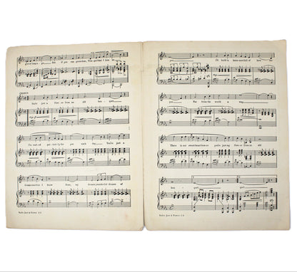 An open vintage sheet music book displaying printed musical notation on aged, yellowed pages against a plain white background.