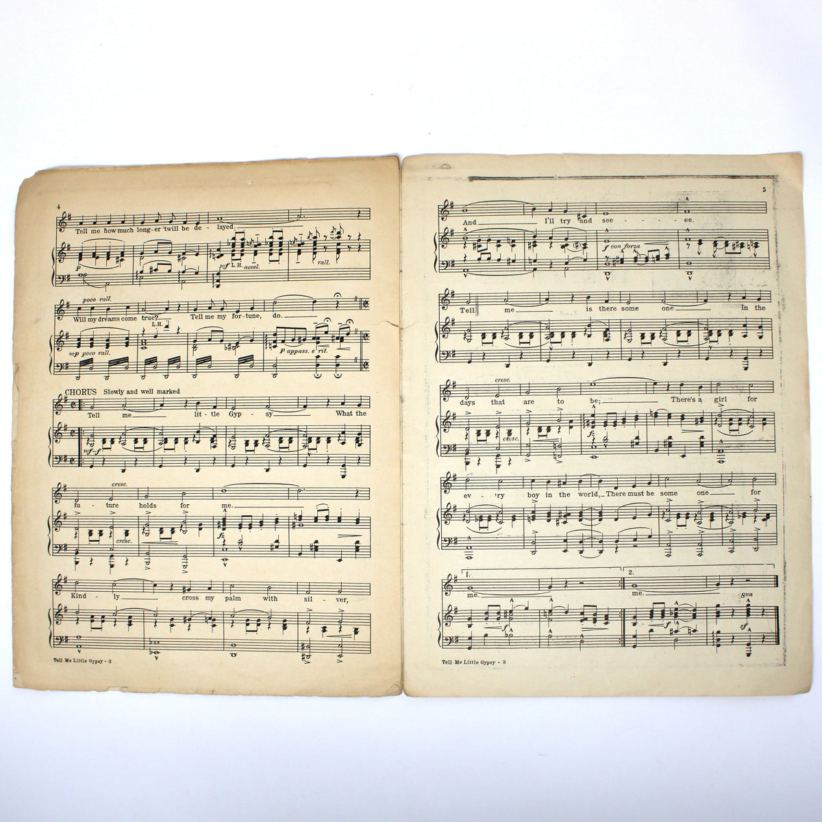An open vintage music book showing two pages of printed sheet music with aged yellowed paper and black musical notation, photographed against a plain white background.