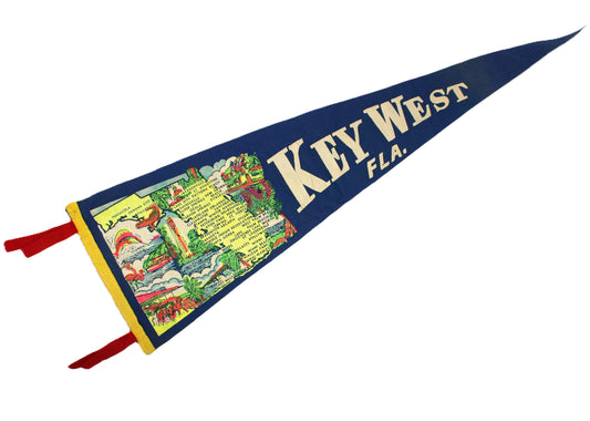 A vintage triangular pennant flag featuring the text 'KEY WEST FLA.' in cream lettering on a dark blue background, with a colorful illustrated map panel on the left and red tassels at the corners.