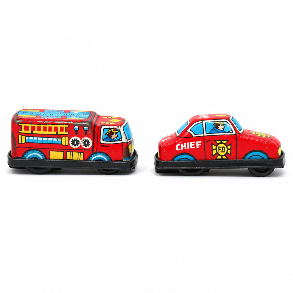 Two vintage mini toy fire trucks side by side. One shaped like a fire engine and the other like a car with 'CHIEF' written on the side.