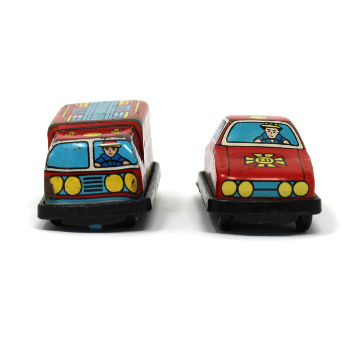 Two vintage mini tin toy cars side by side: a red and blue fire engine on the left and a red fire chief car on the right.