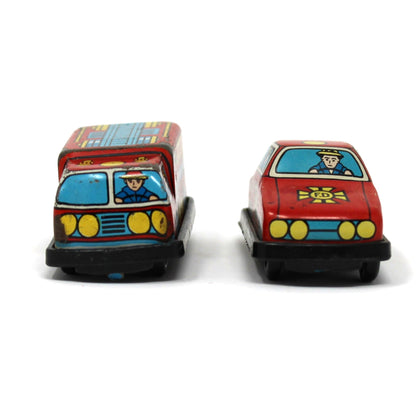 Two vintage mini tin toy cars side by side: a red and blue fire engine on the left and a red fire chief car on the right.