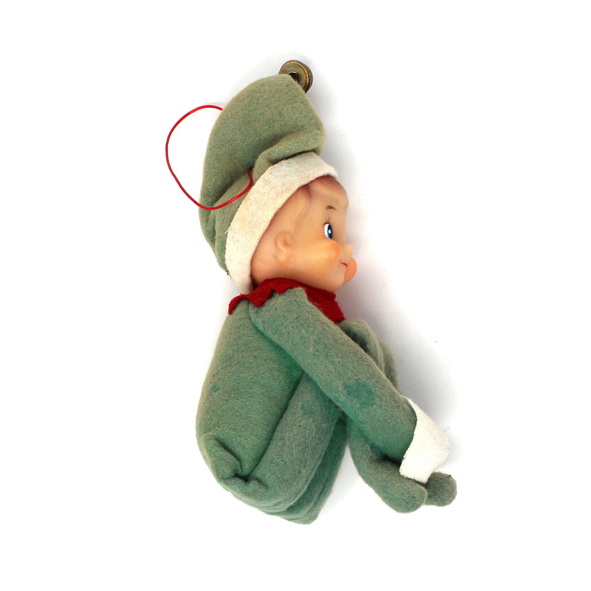A vintage Christmas elf ornament featuring a small doll dressed in a green suit and hat with a red collar, set against a plain white background.