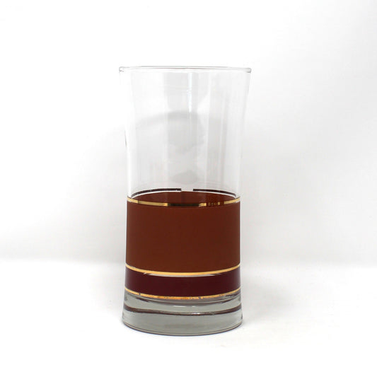 A clear glass tumbler with a flared rim, partially filled with a dark amber-brown liquid, set against a plain white background.