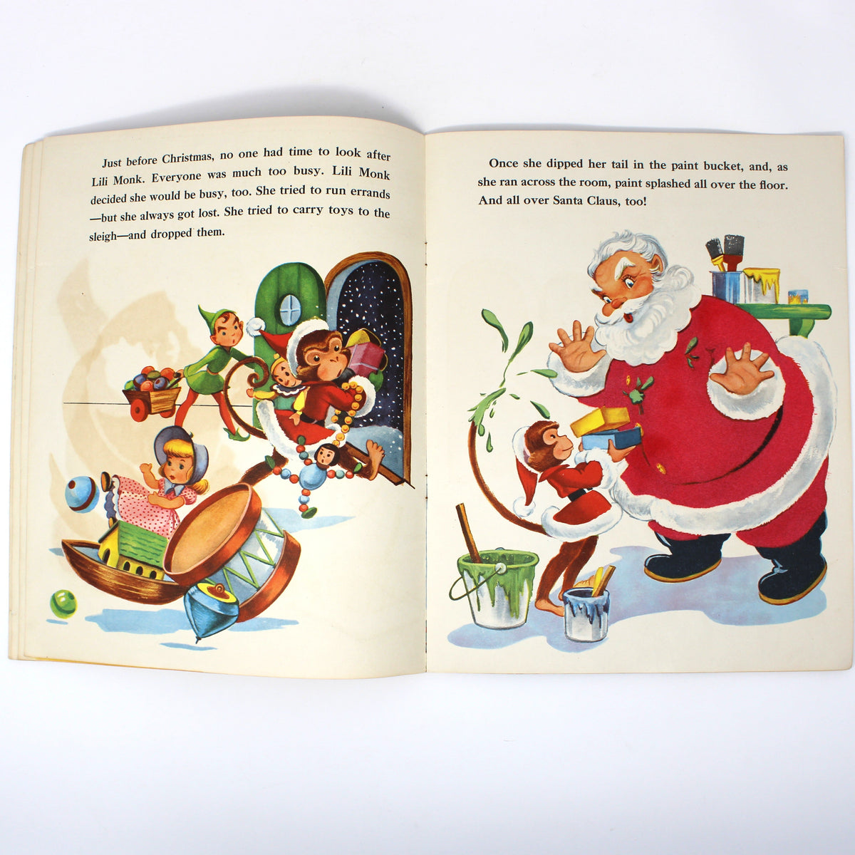 An open vintage children's book spread on a white background, showing illustrated holiday scenes with Santa Claus, elves, and children on the pages.