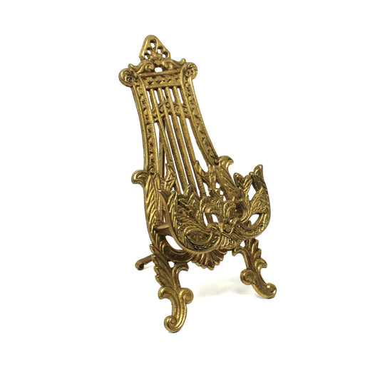 An ornate antique-style brass lyre-shaped tabletop easel stand .