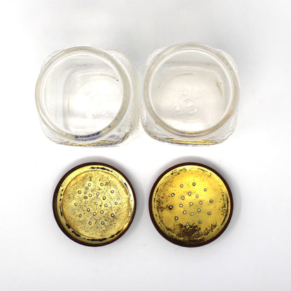 View of vintage salt and pepper glass jars opened plus their lids turned upside down to show the inside.  