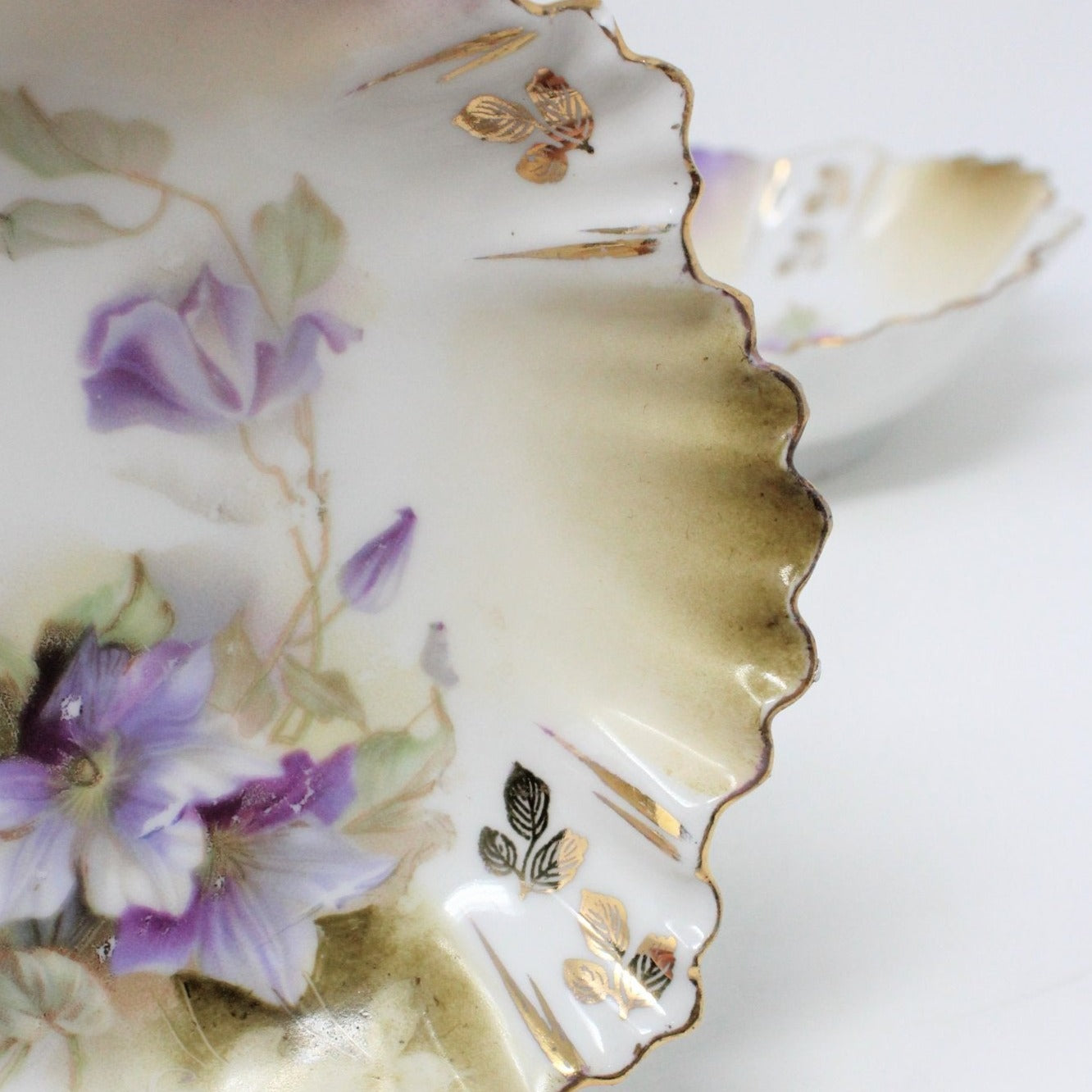 Close up of beautiful scalloped rim with gold hand painted flowers on border